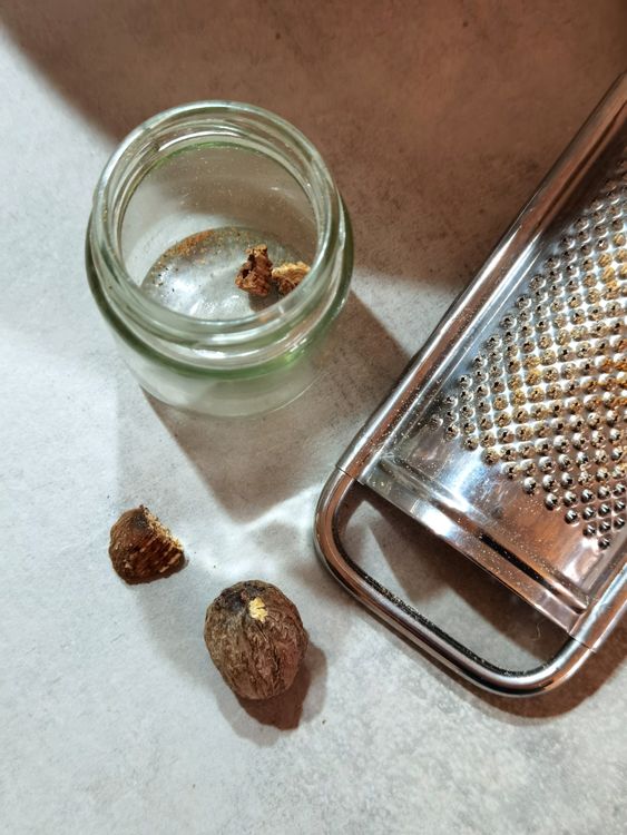 Whole nutmeg with a grater on a kitchen counter