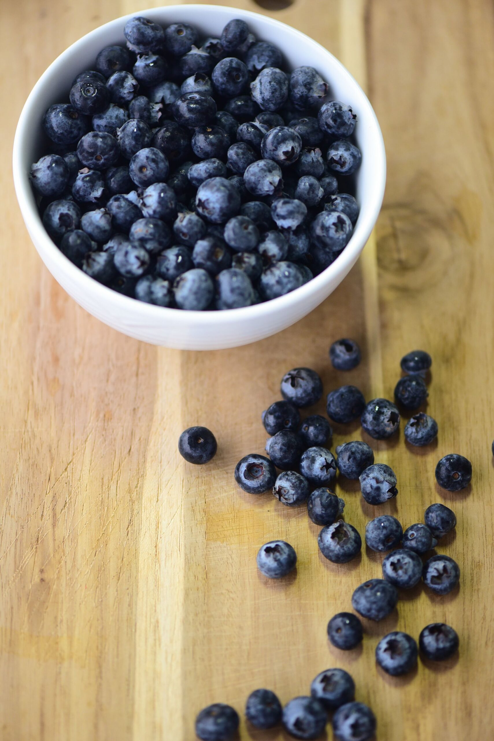 A bowl of fresh blueberries on a wooden table